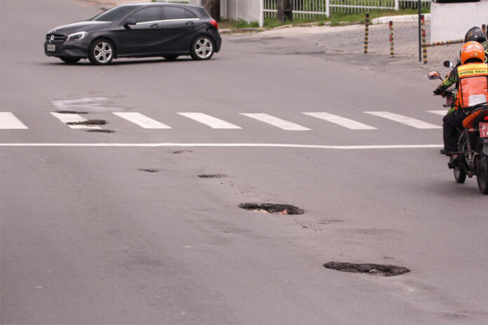 Buracos em trecho na Alameda Cosme Ferreira foram causados por ônibus que freiam para pegar passageiros na plataforma de transporte público.