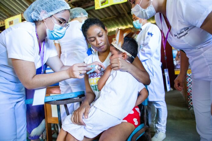 Criança indígena recebe vacina durante campanha de mobilização, em Manaus.