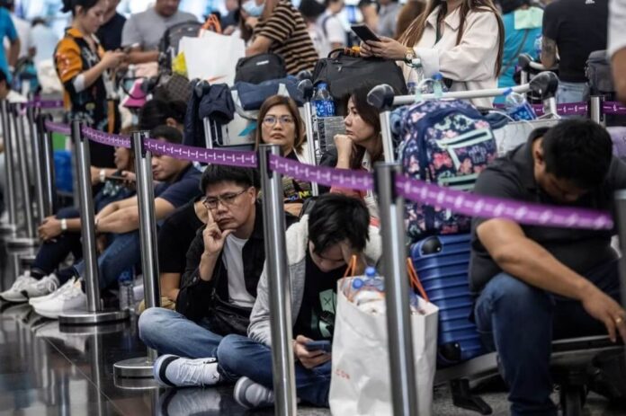 Passageiros aguardando check-in manual no Aeroporto Internacional de Hong Kong, devido ao apagão cibernético.